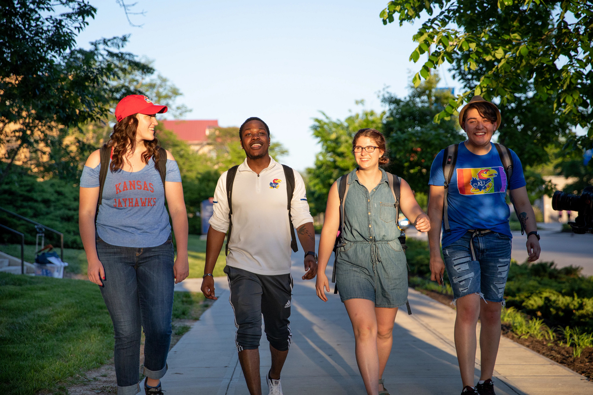 four students walking together on campus, facing the camera and smiling