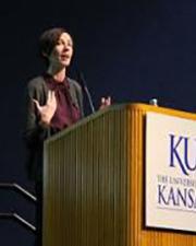 Abigail Barefoot standing behind a lectern speaking into a microphone