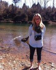 Kelsey Carls standing outdoors in a shallow creek bed