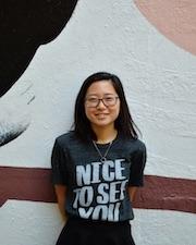 Melinda Chen standing in front of a mural smiling